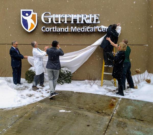 People unveiling building sign