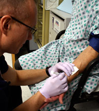 nurse inserting needle in patients arm