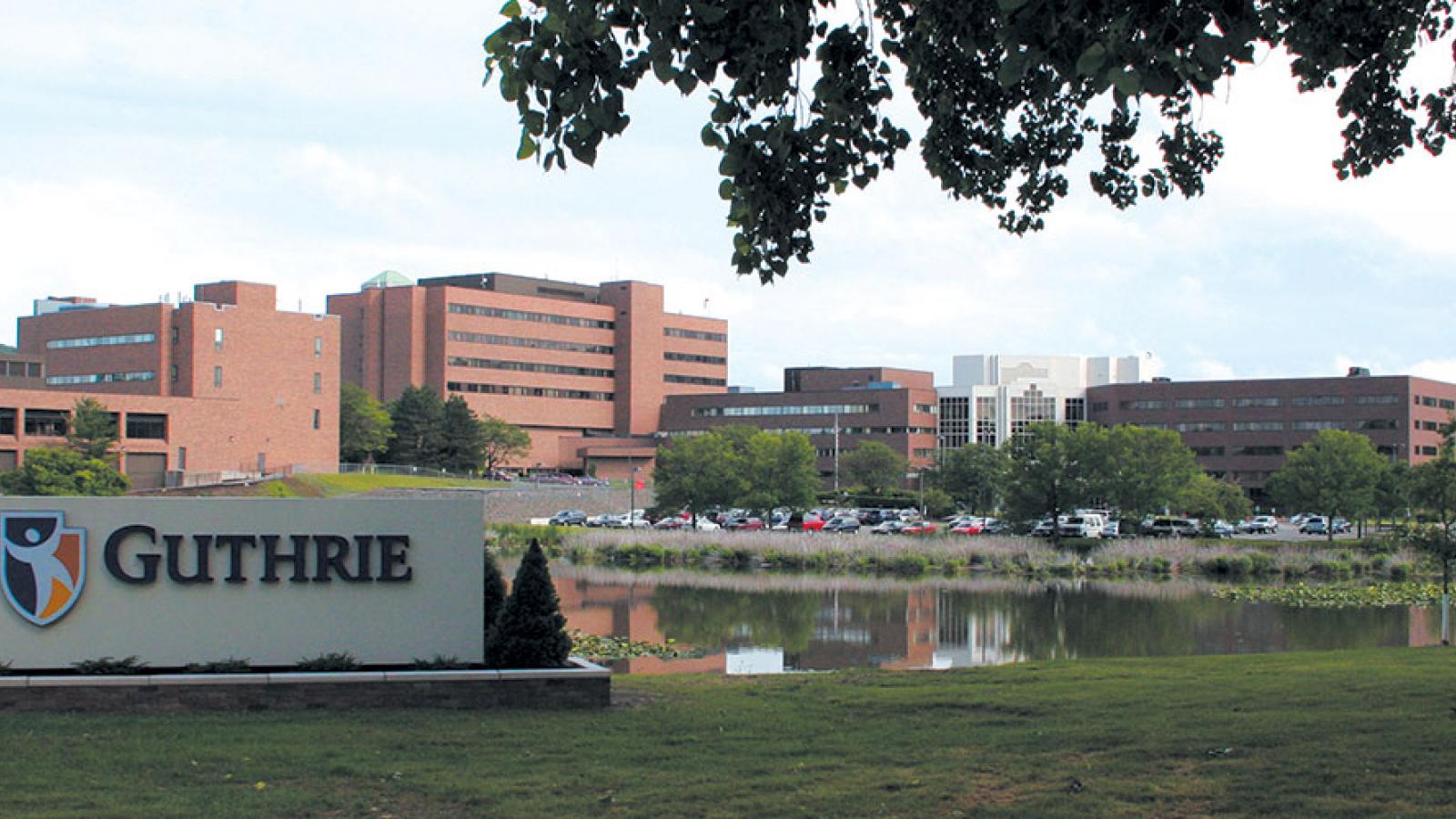Guthrie sign with campus in the background 