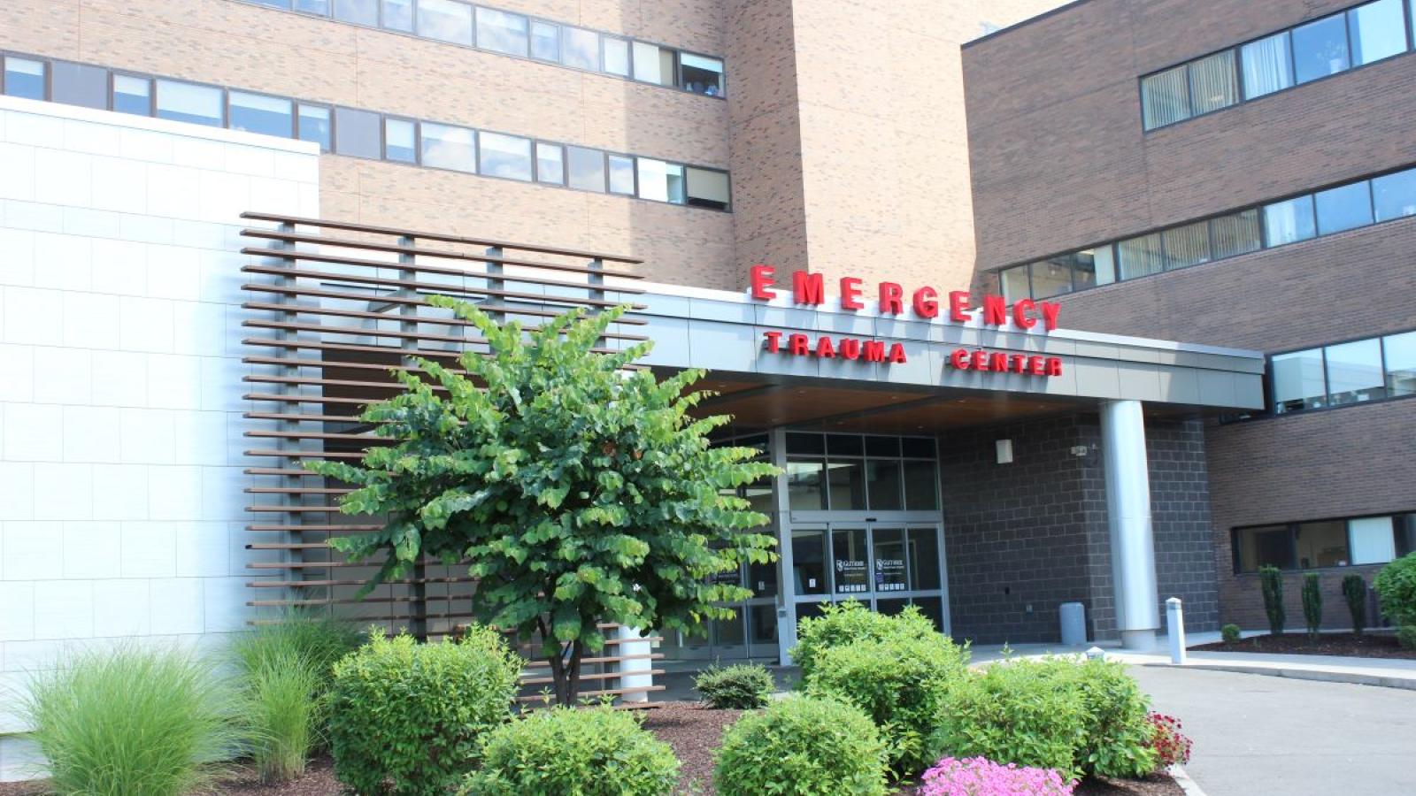 Daytime photo of brick hospital building and entrance sign that reads "Emergency Trauma Center."