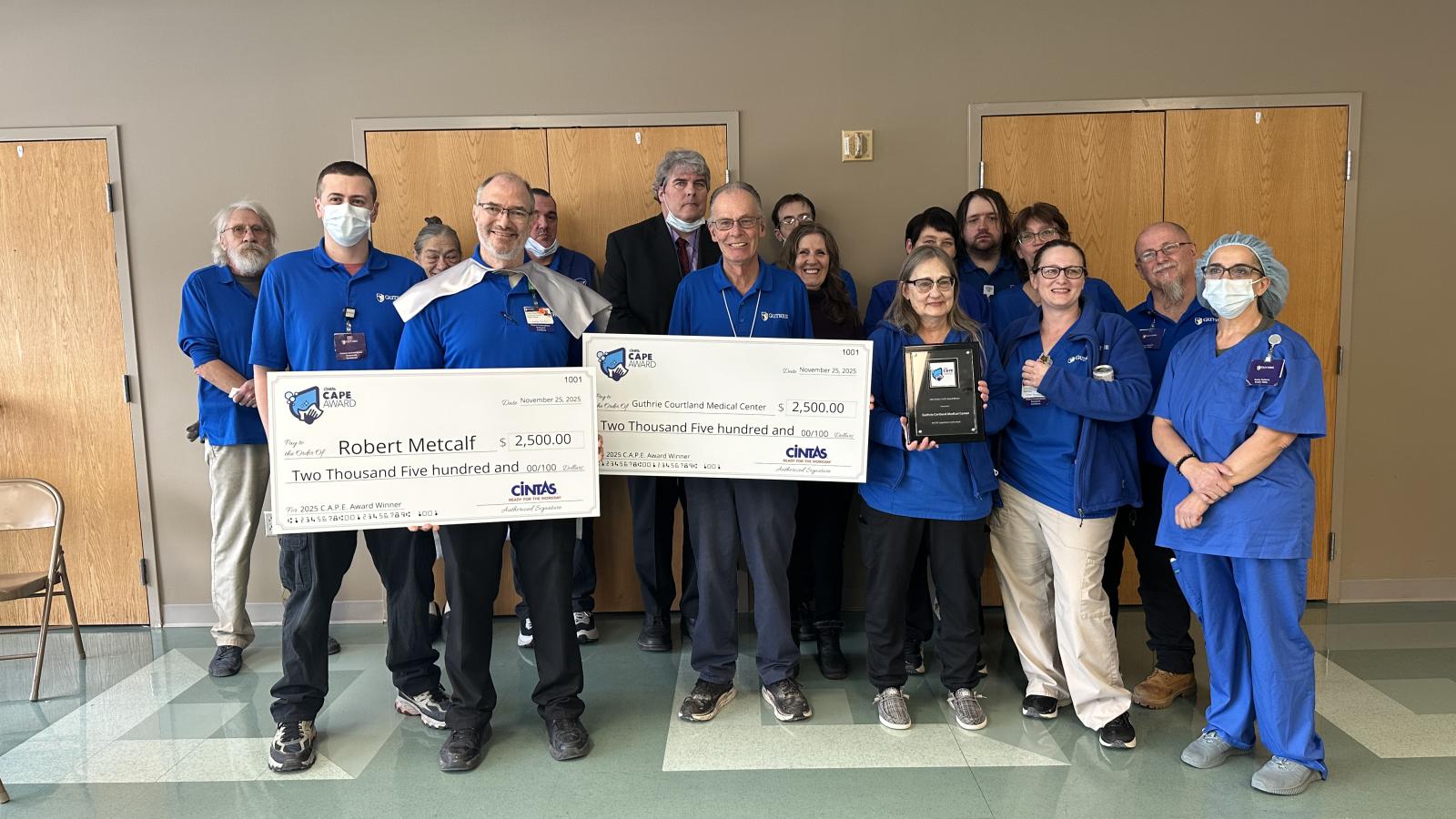 Robert Metcalf (front row, second from left), holds the check he received as part of the C.A.P.E., AWARD. He is surrounded by his EVS team, representatives from Cintas, and Guthrie Cortland Medical Center leadership.  