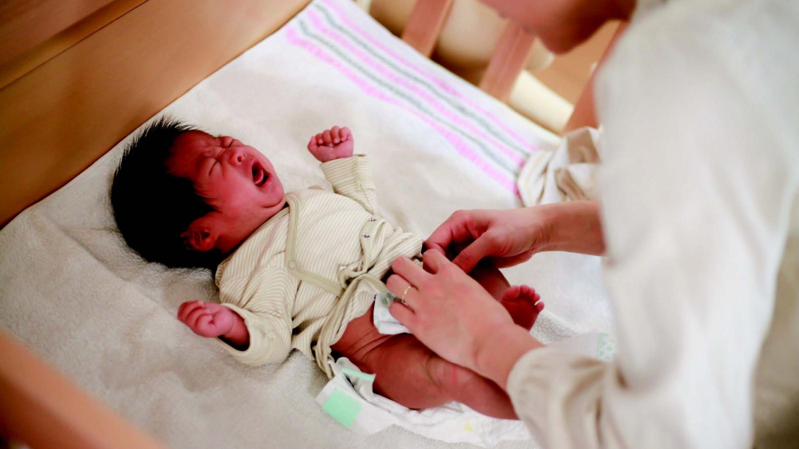 A woman changes a baby's diaper.