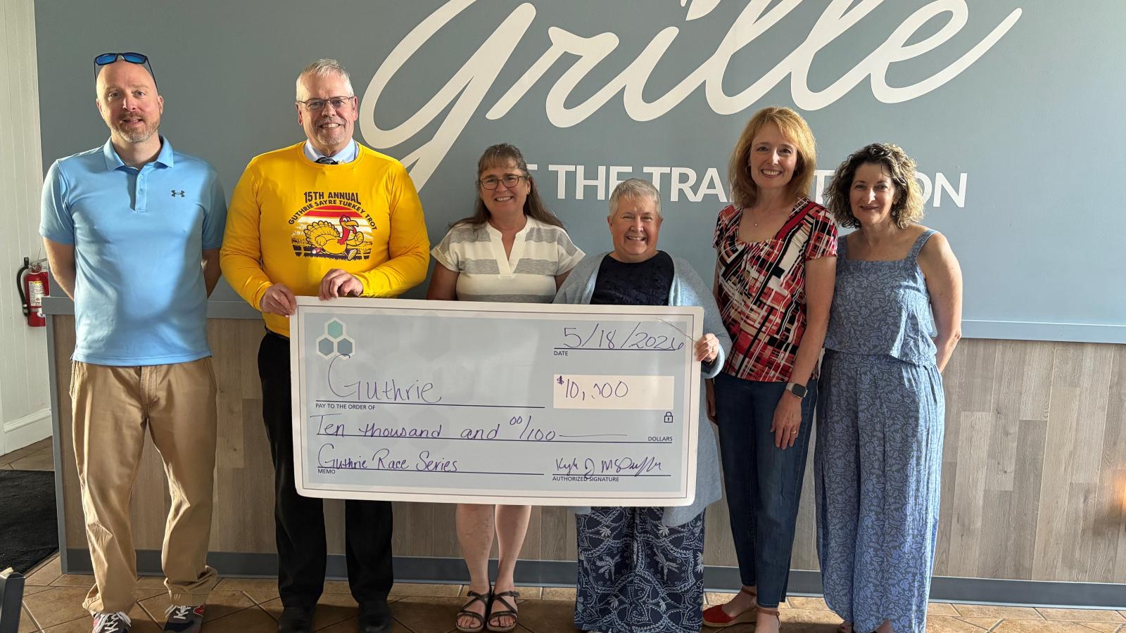A group of individuals stand holding a large check.