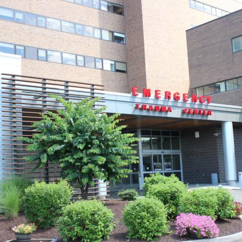 Daytime photo of brick hospital building and entrance sign that reads "Emergency Trauma Center."