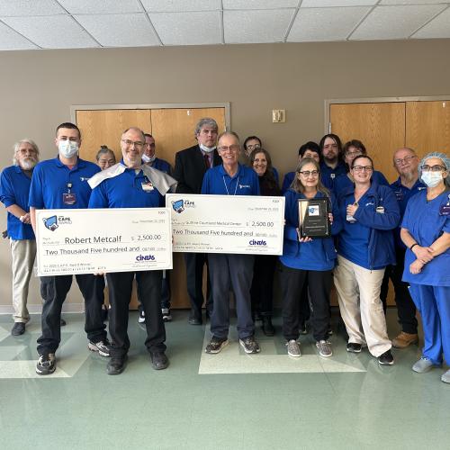 Robert Metcalf (front row, second from left), holds the check he received as part of the C.A.P.E., AWARD. He is surrounded by his EVS team, representatives from Cintas, and Guthrie Cortland Medical Center leadership.  