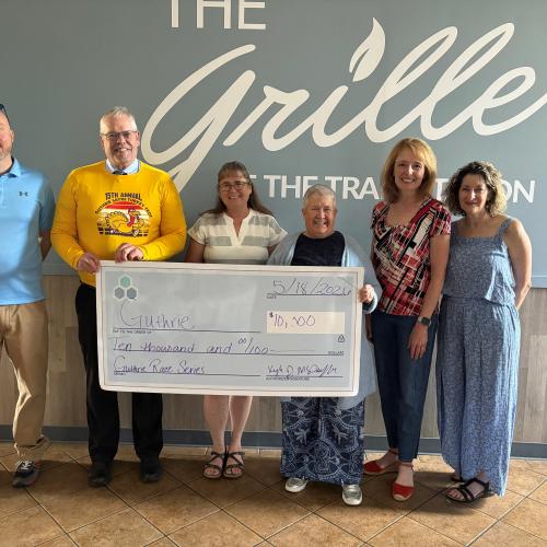 A group of individuals stand holding a large check.
