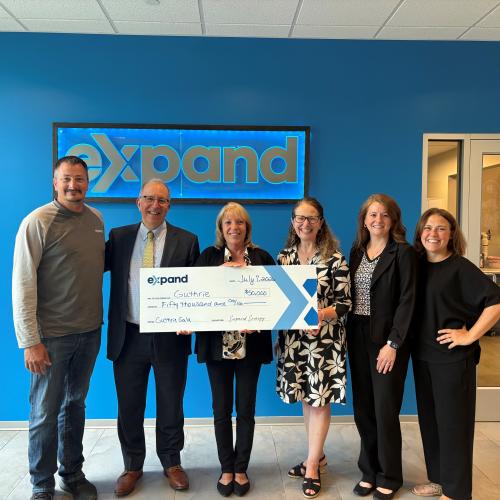 A group of people pose while holding a large check.